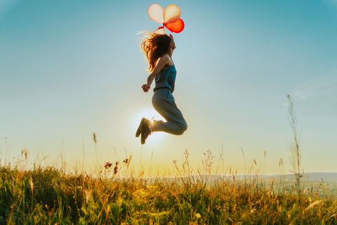 Neumondhoroskop: Eine Frau mit Luftballons springt in die Luft