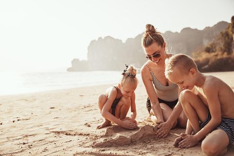Wertsachen beim Baden verstecken: Mutter baut mit ihren zwei Kindern eine Sandburg