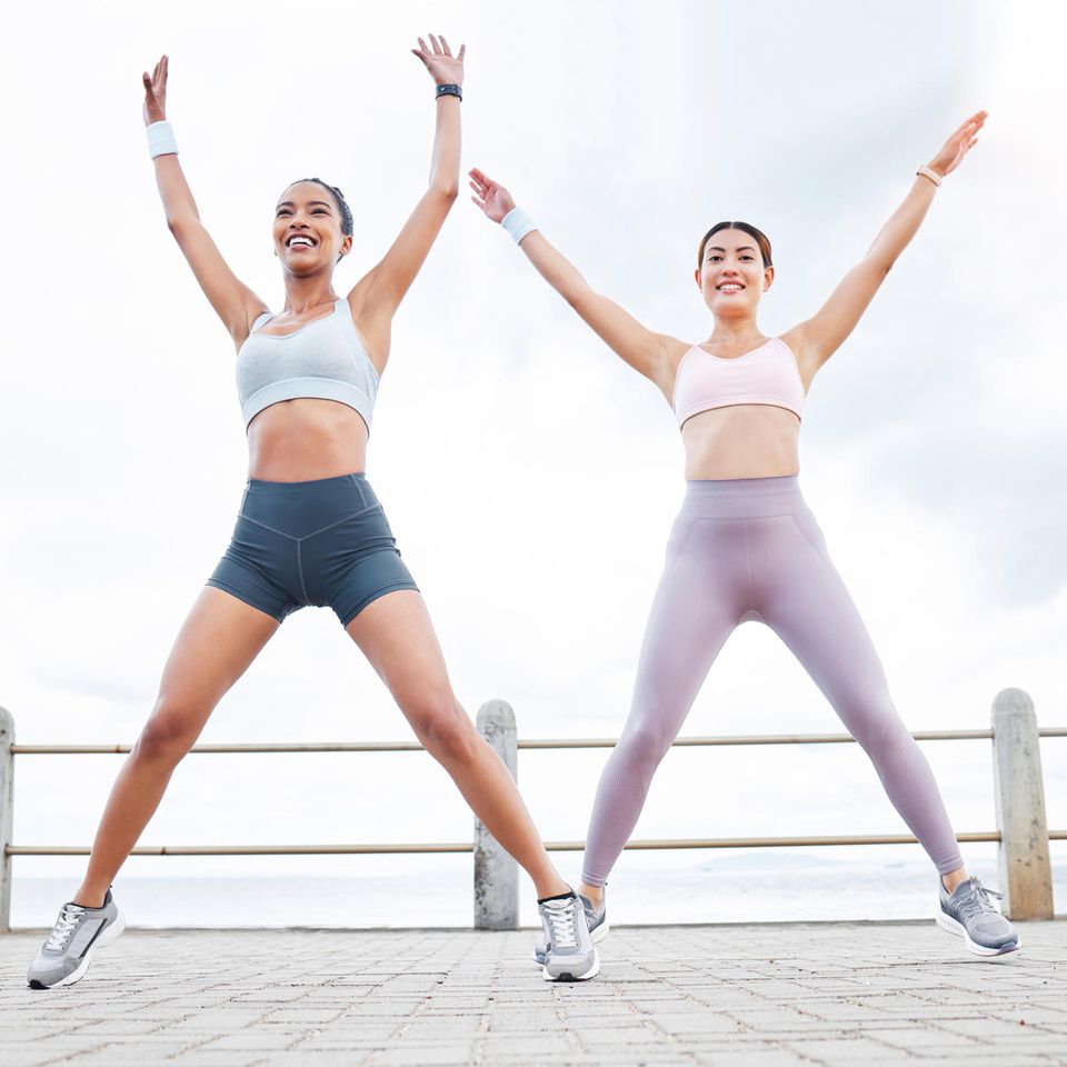 Zwei Frauen machen draußen Jumping Jacks: Das passiert, wenn du jeden Tag diese Kinderübung machst