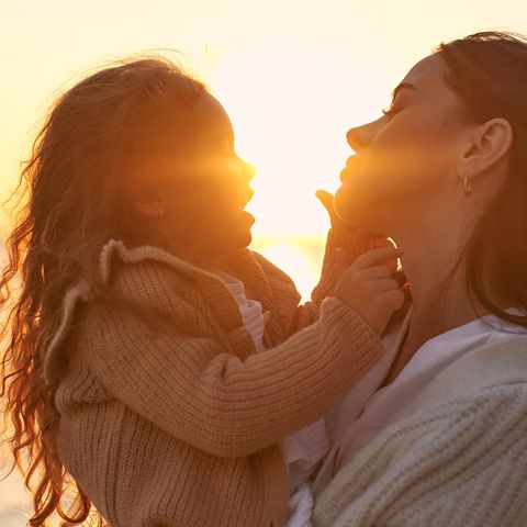 Mutter und Tochter einander zugewandt am Strand bei Sonnenuntergang