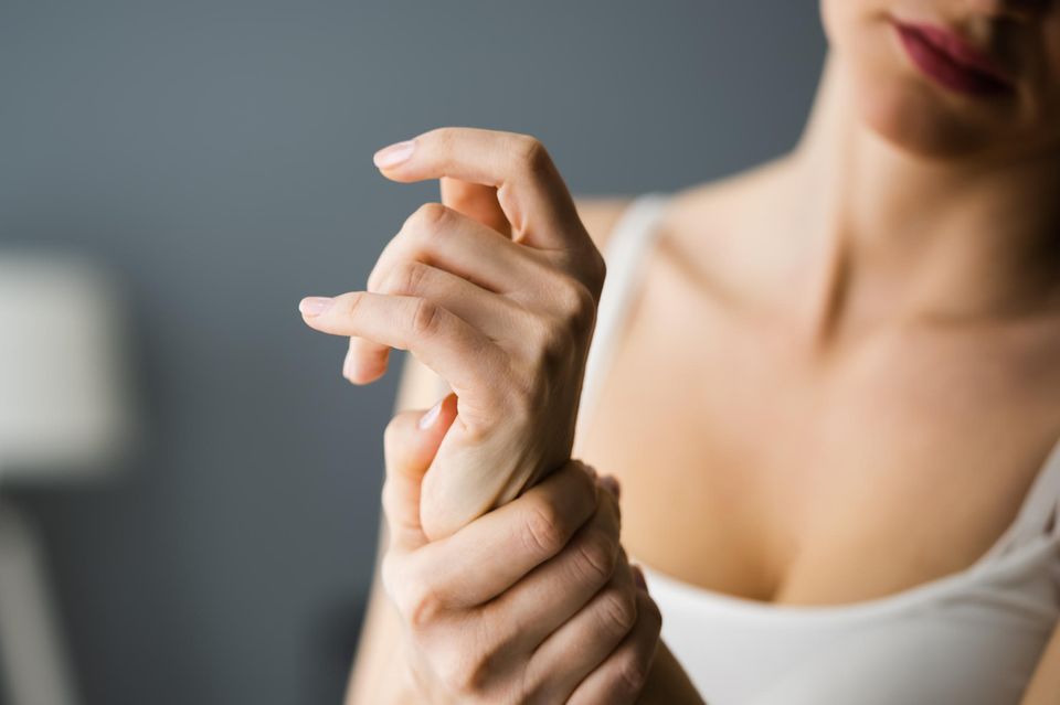 Gelenkschmerzen in den Wechseljahren: Frau hält sich das Handgelenk