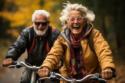 Ältere Frau sitzt glücklich auf dem Fahrrad (KI generiert)
