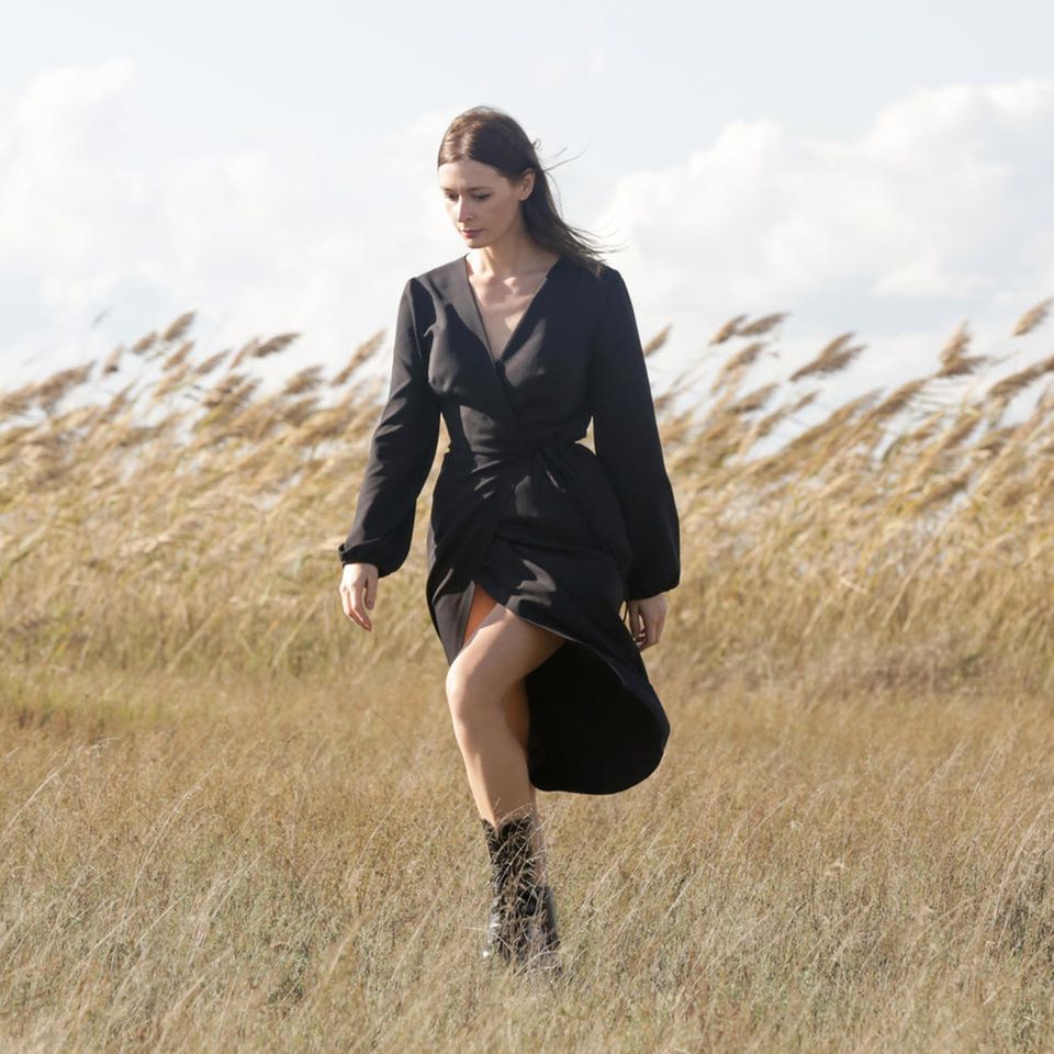 Wickelkleider Trend 2023: Eine Frau läuft in einem Wickelkleid über ein Feld