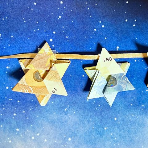 Geldscheine zum Stern falten: Origami-Sterne aus Geldscheinen auf einem Himmel-Hintergrund