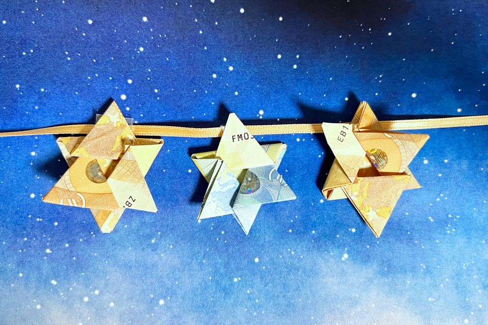 Geldscheine zum Stern falten: Origami-Sterne aus Geldscheinen auf einem Himmel-Hintergrund