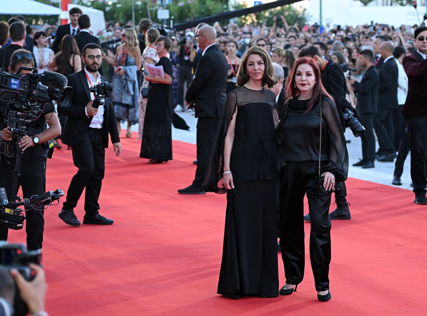 Regisseurin Sofia Coppola und Priscilla Presley sind bei der Weltpremiere in Venedig natürlich auch auf dem roten Teppich, beide in ähnlichen Looks mit Sheer-Details in Schwarz, Sofia im Cape-Dress, Priscilla im seidigen Blusen-Hosen-Ensemble.