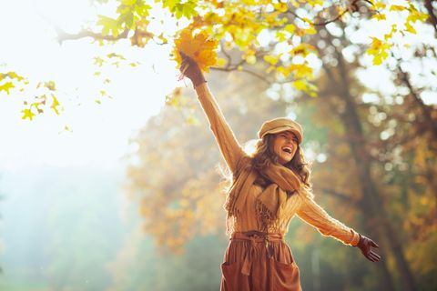 Frau jubelt im Herbstlaub 1.5004