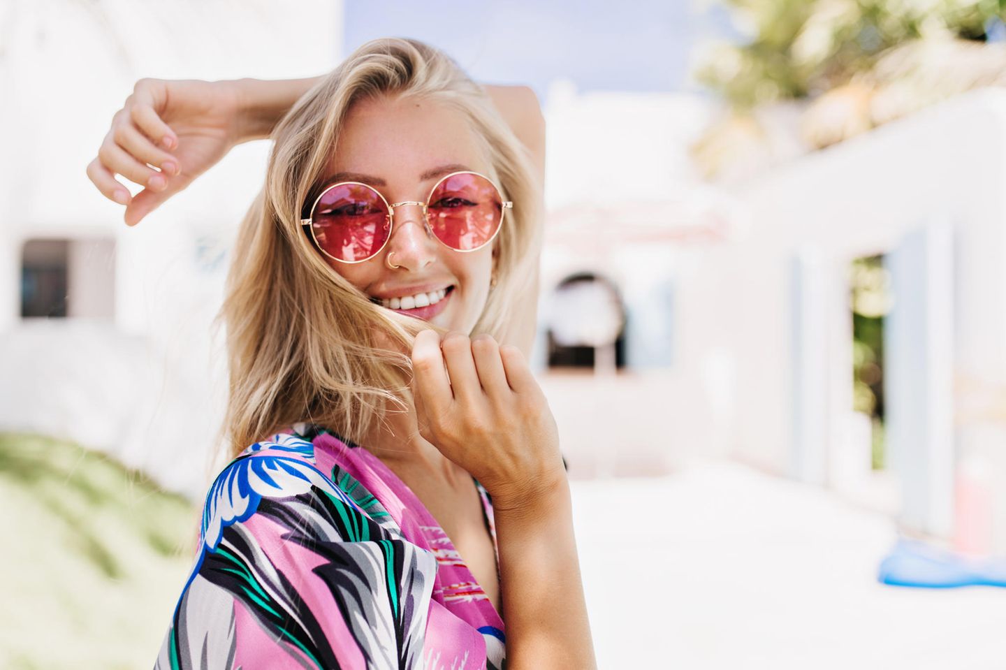 Glückliche Frau mit blondem Haar und rosa Sonnenbrille