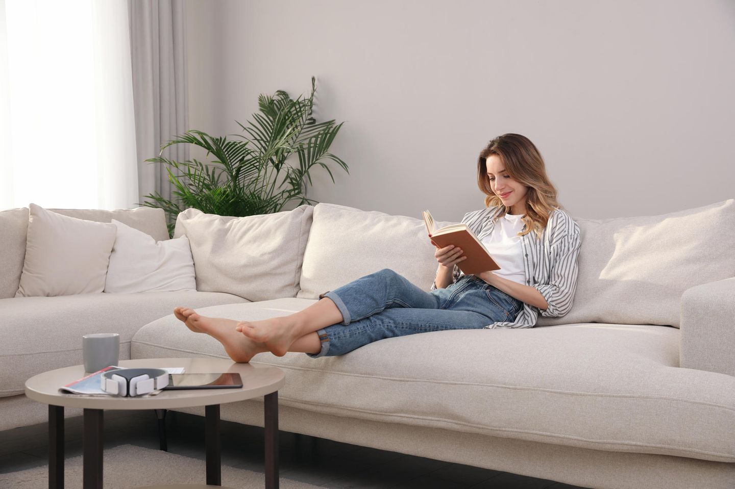 Bücher Herbst 2023: Frau liest ein Buch auf dem Sofa