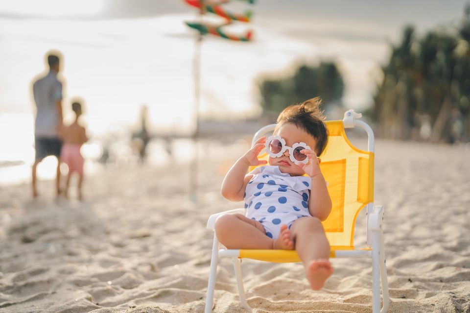 Baby mit Sonnenbrille liegt im Strandstuhl in der Sonne Kaliforniens