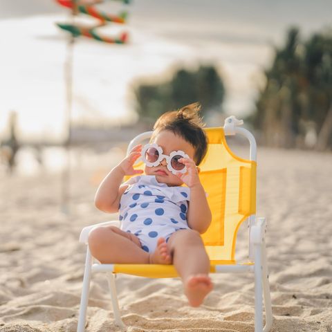 Baby mit Sonnenbrille liegt im Strandstuhl in der Sonne Kaliforniens