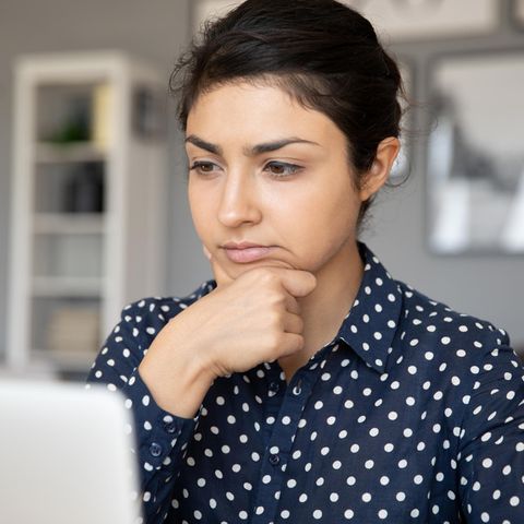Frau schaut nachdenklich auf ihren Laptop