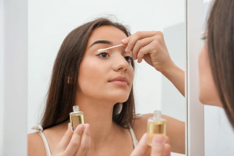 Wimpernserum ohne Hormone: Eine Frau trägt mit einem Wattestäbchen ein Serum auf ihre Wimpern auf
