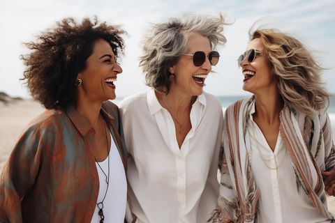 Drei Frauen am Strand lachen miteinander