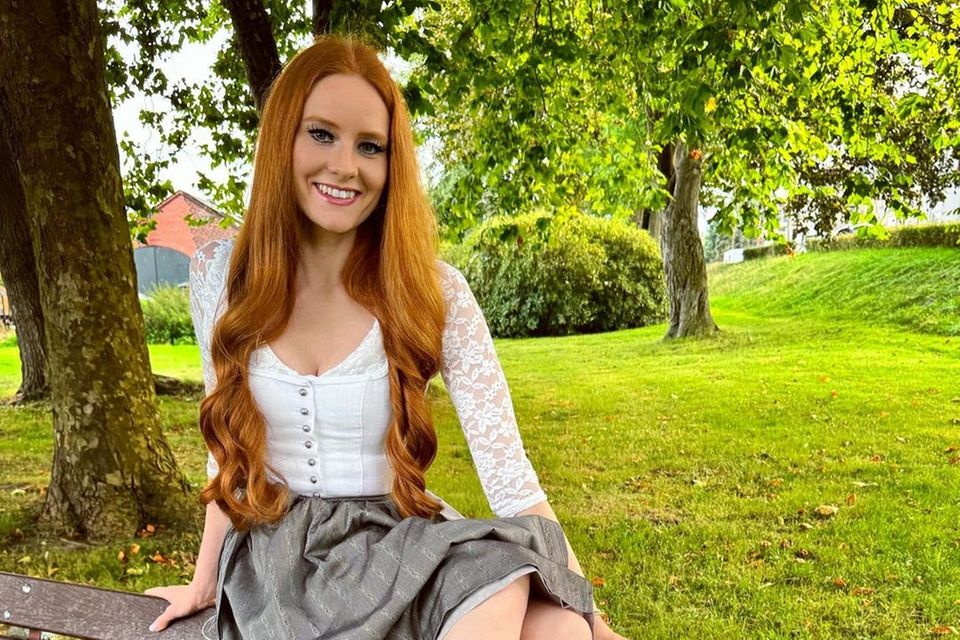 Barbara Meier hat sich zu ihrem weißen Spitzendirndl mit grauer Schürze bequemes Schuhwerk von Rieker ausgesucht, damit sie auf der Wiesn ausgelassen und ohne Fußschmerzen mit ihren Freund:innen tanzen kann. 