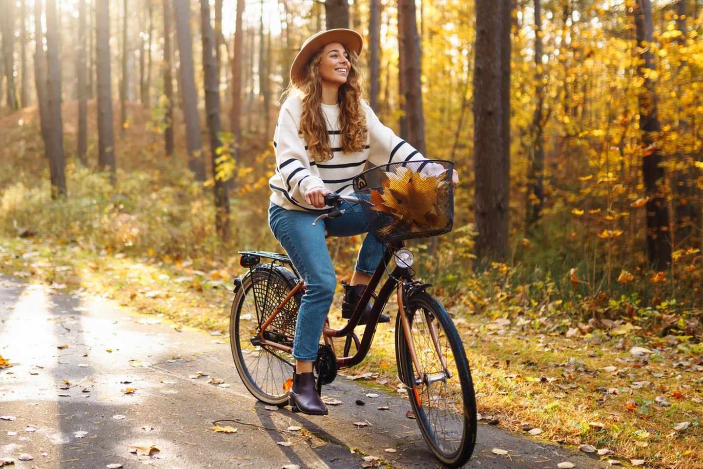 Deals des Tages: Levi's 501 Crop um 50% reduziert, Frau mit Hut auf Rad im Herbst