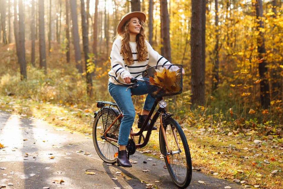 Deals des Tages: Levi's 501 Crop um 50% reduziert, Frau mit Hut auf Rad im Herbst