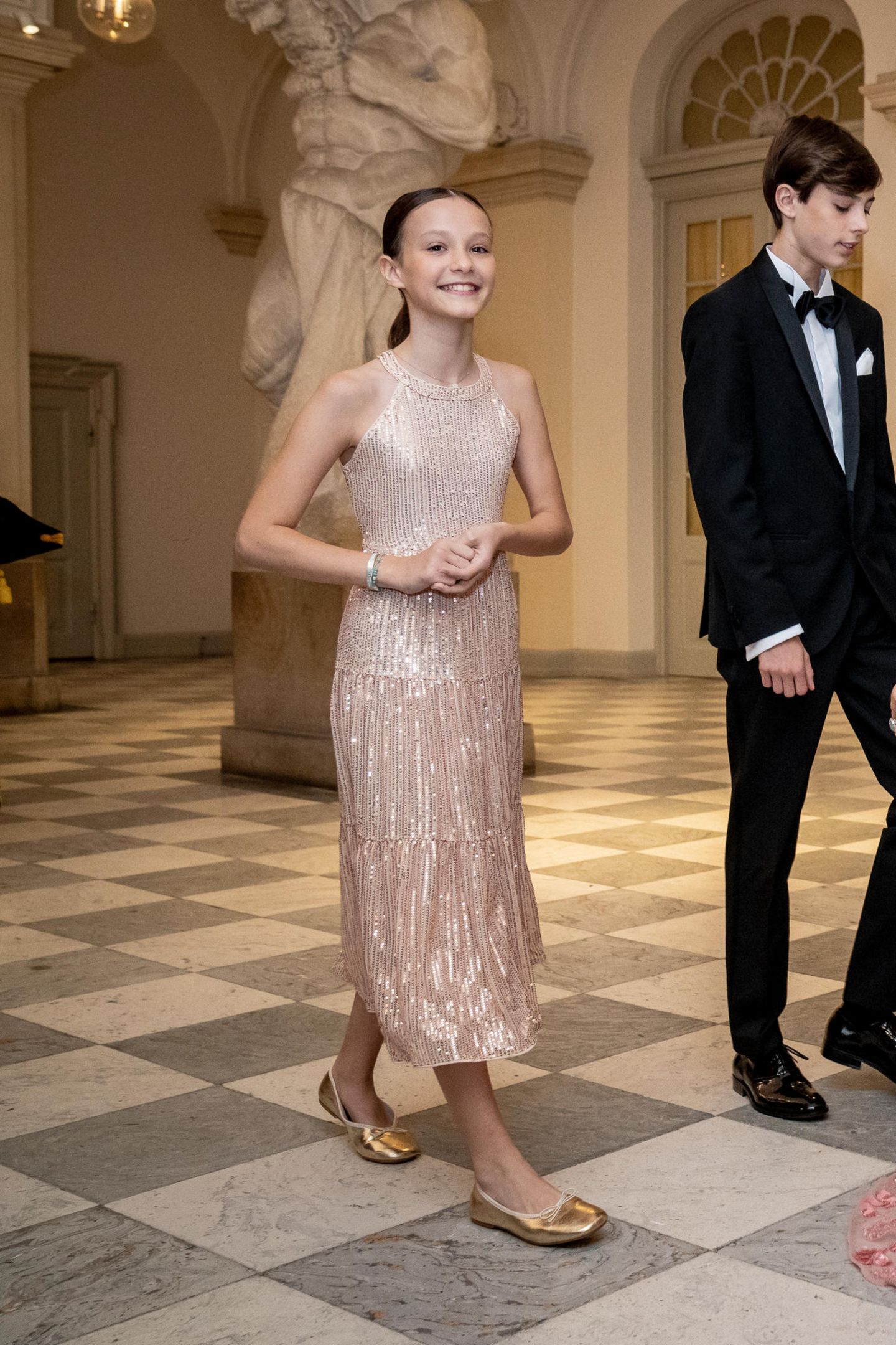 Es ist ihr erster Auftritt im Abendkleid: Athena zu Dänemark, die Tochter von Prinz Joachim bezaubert zum Geburtstagsbankett ihres Cousins in einem cremefarbenen Paillettenkleid und goldenen Ballerinas. Die Haare hat sich die junge Dänin zu einem süßen Pferdeschwanz frisieren lassen.