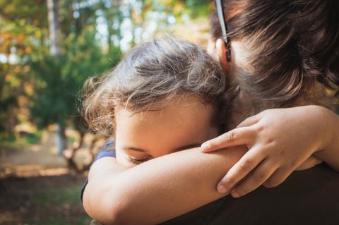 Familienhörbuch: Kind umarmt seine Mutter im Sonnenschein