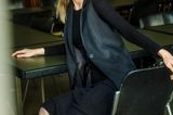 Model sitzt im schwarzen Outfit auf einem Stuhl