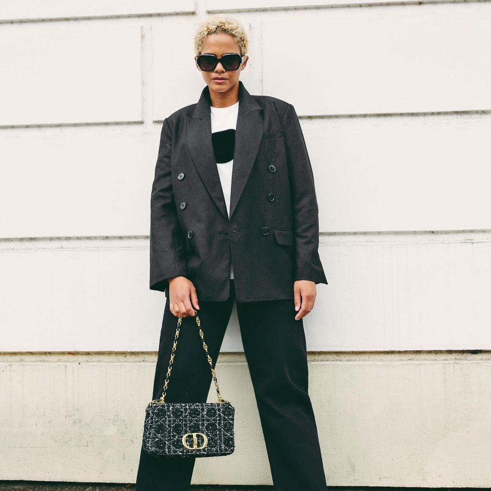 Für einen klassischen Business Casual Look ist der doppelreihige Blazer von &Other Stories mit der fransigen Jeans von Lovjoi perfekt geeignet. Um einen farblichen Kontrast zu setzen kombiniert das Model einen weißes T-Shirt mit schwarzem Plüsch-Punkt und stylische Loafer. Die Prada-Sonnenbrille sowie die Handtasche von Christian Dior machen den eleganten Look komplett. 