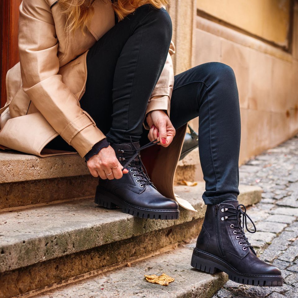 Die perfekten Herbststiefel: Eine Frau schnürt ihr Stiefel draußen auf einer Treppe