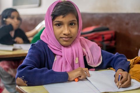 Indien: Ein Mädchen sitzt in einer Schulklasse