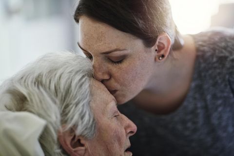 Eine Frau küsste eine Seniorin liebevoll auf die Stirn