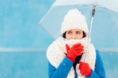 Expertentipps: Eine Frau mit dicker Mütze und Schal und einem Regenschirm