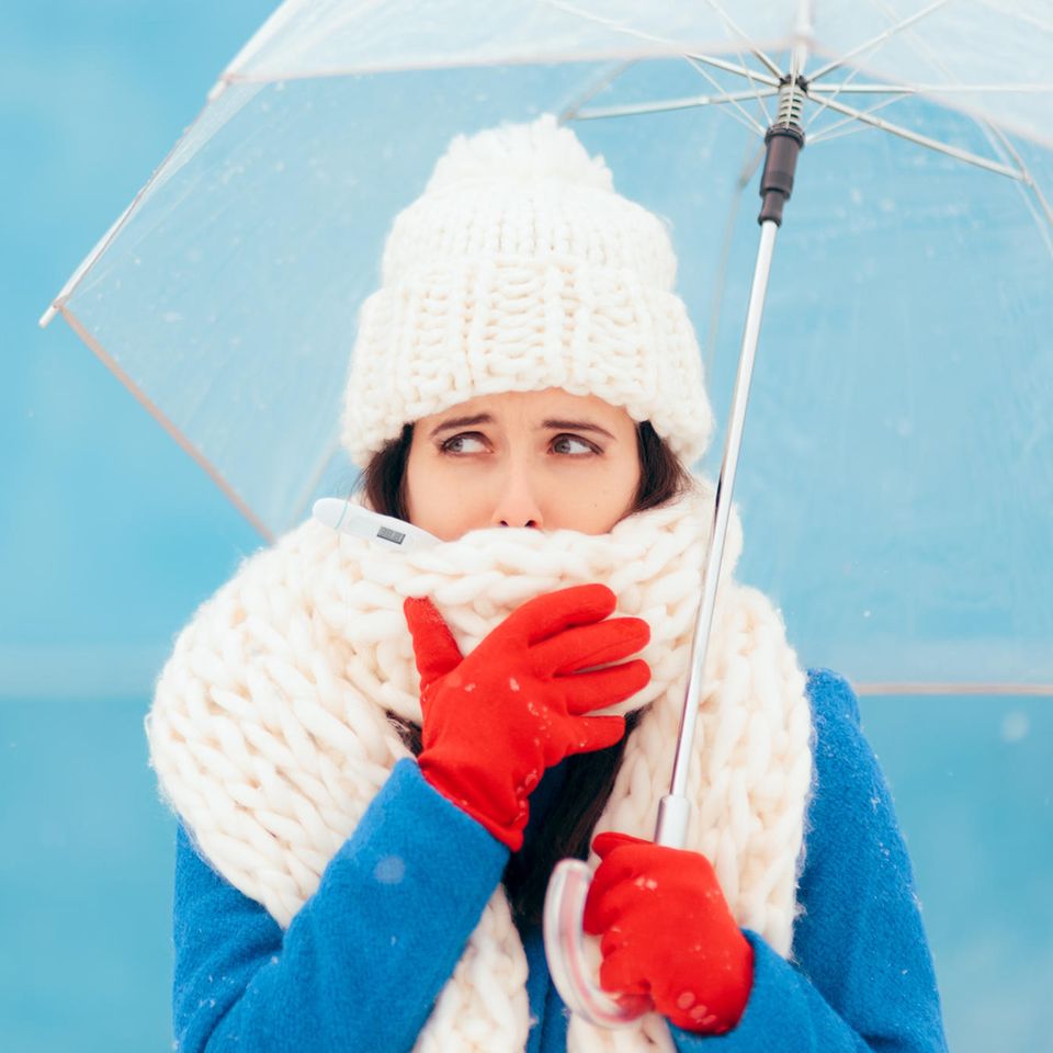 Expertentipps: Eine Frau mit dicker Mütze und Schal und einem Regenschirm