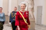 Prinzessin Benedikte präsentiert sich beim großen Dinner im Schloss Christiansborg in einem glänzenden roten Seidenkleid. Ihre Haare trägt sie hochgesteckt, ihre Tiara blendet sich darin wunderbar ein. Eine große Halskette und die gelbe Schärpe runden ihr Styling ab. 