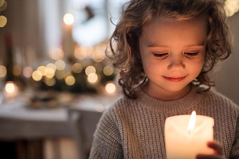 Gedenkkultur: Kind mit Kerze gestaltet Ahnenaltar