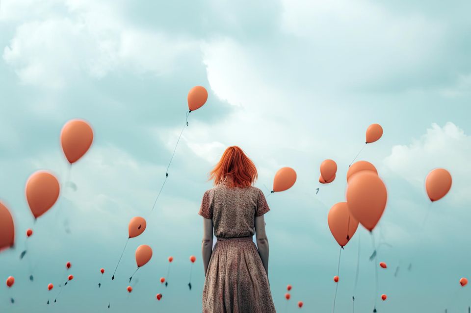 Trauer: Frau zwischen aufsteigenden Luftballons