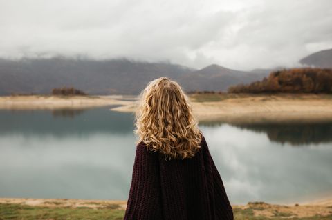 Frau schaut auf Wasser und Berge: 4 Anzeichen, dass die Vergangenheit dich gefangen hält