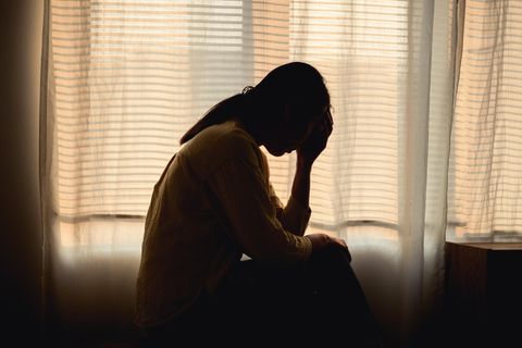 Weltschmerz: traurige Frau sitzt in abgedunkeltem Zimmer