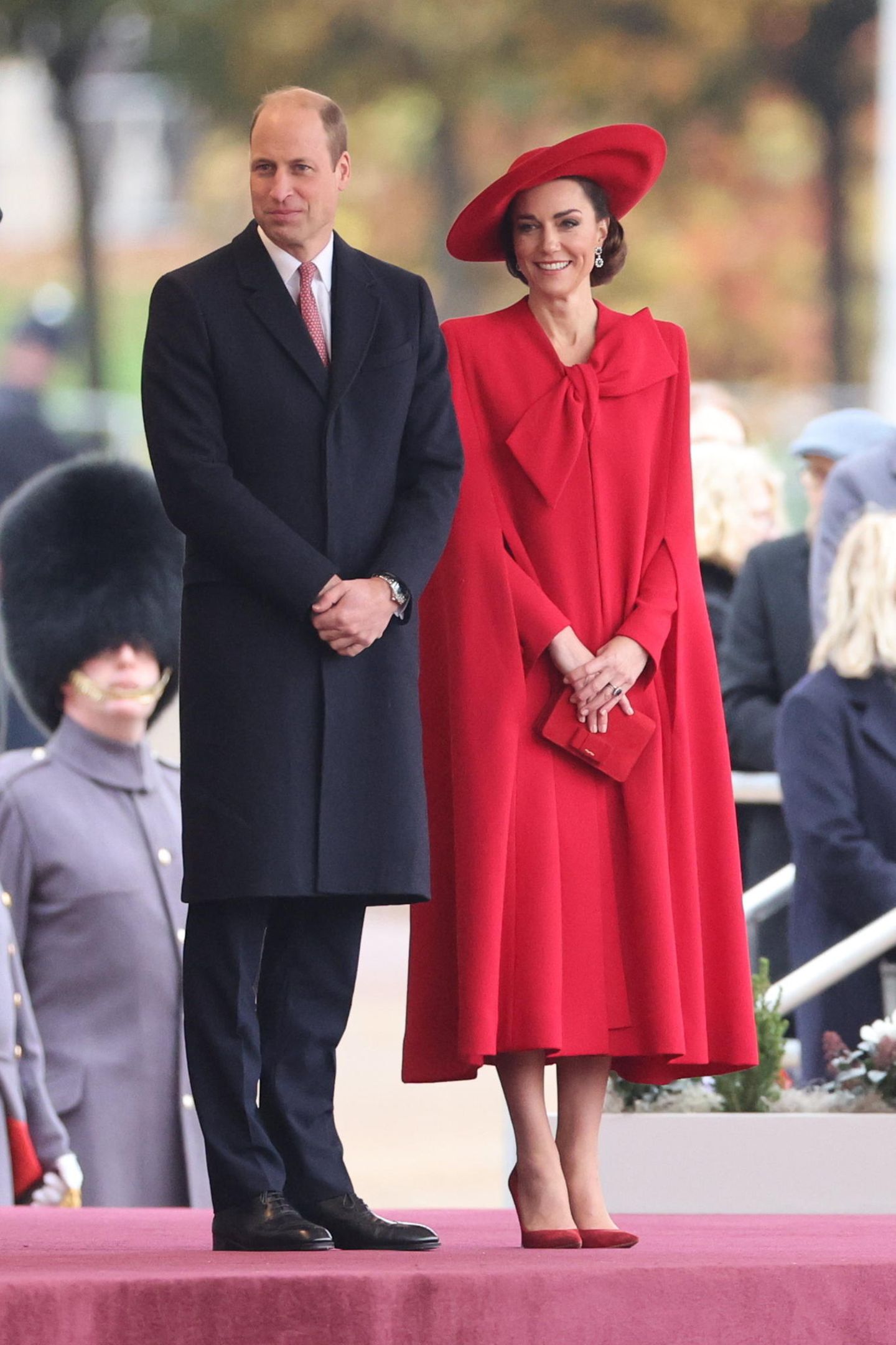 Prinz William und Catherine, Princess of Wales, empfangen Staatsbesuch aus Südkorea. Vor allem Kate begeistert bei der Begrüßungszeremonie in einem roten Wow-Look. Sie trägt ein rotes Cape-Dress mit großer Schleife von Catherine Walker, das an ihren Look vom Weihnachtsgottesdienst 2021 erinnert. Dazu trägt sie einen farblich passenden Hut, eine kleine Clutch, Veloursleder-Pumps und ihre Saphir-Diamant-Ohrringe, die dem Design ihres Verlobungsrings entsprechen. 