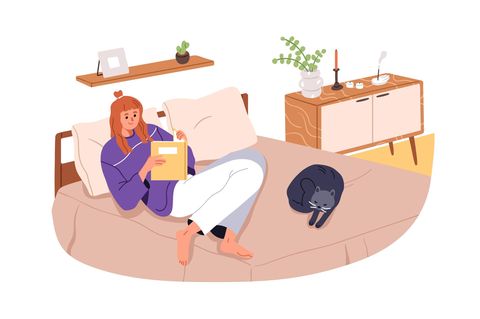 Frau liest auf dem Bett mit Katze: 5 unkitschige Liebesromane, die mehr zu bieten haben als eine reine Lovestory