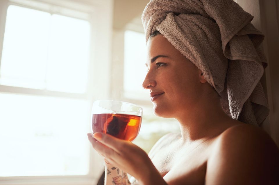 Eine Frau gönnt sich Selfcare zu Hause und trinkt Tee