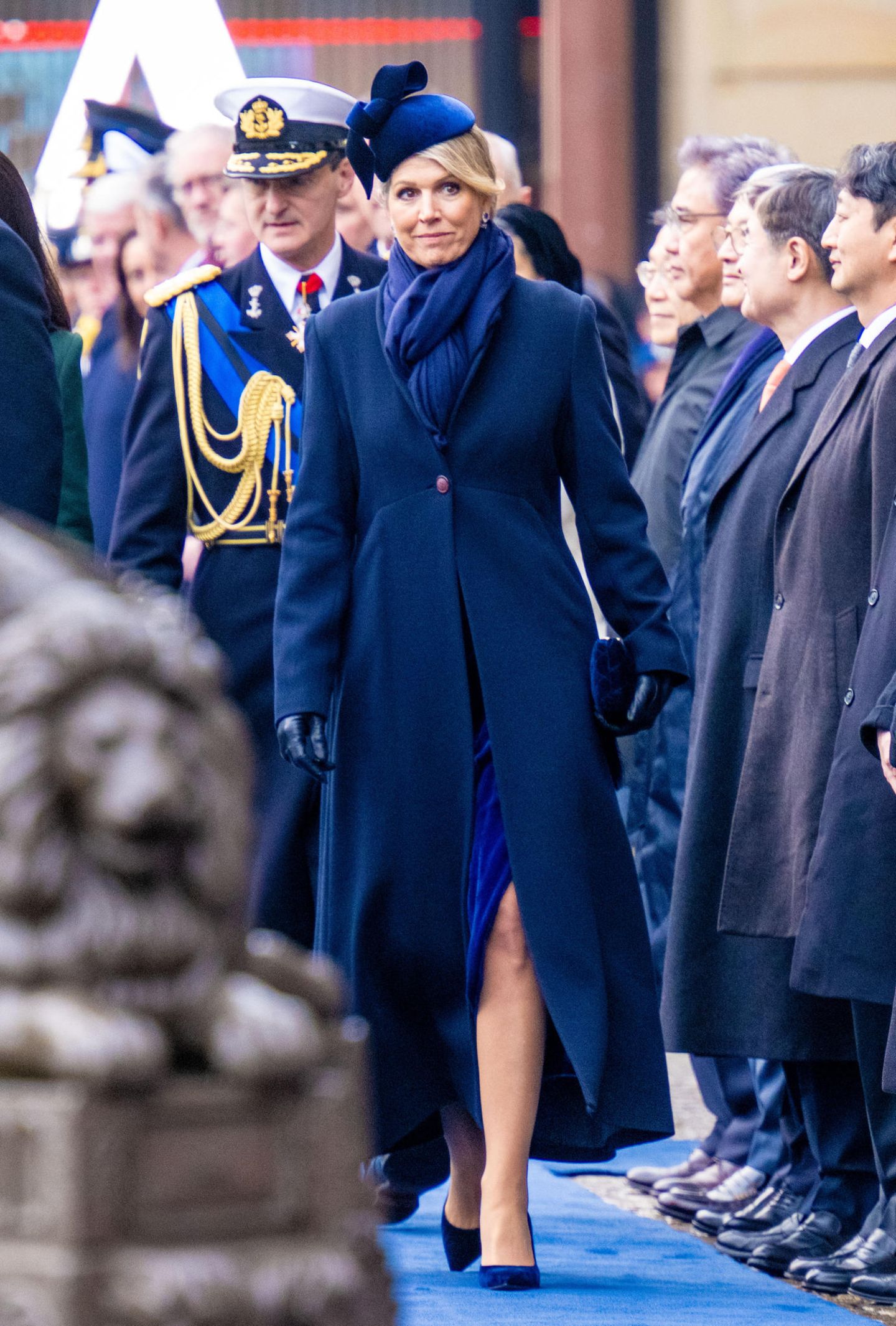 Für die Begrüßung des südkoreanischen Präsidentenpaares auf dem Dam-Platz in Amsterdam hat sich Königin Máxima einen eleganten Mantellook in Navyblau ausgesucht, unter dem ein royalblauer Samtrock hervorblitzt.