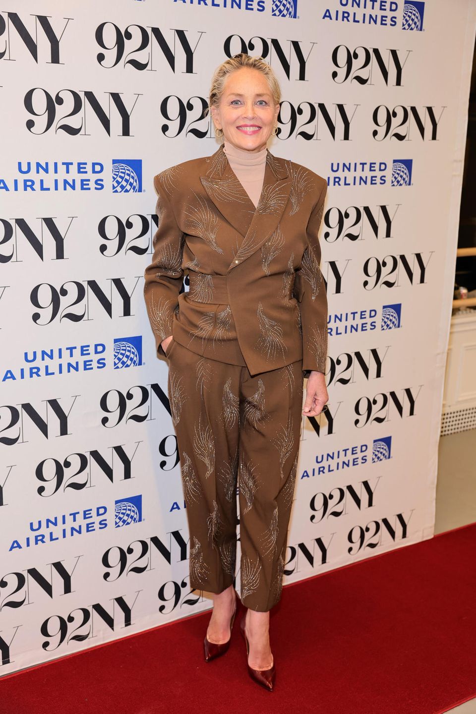Sharon Stone zeigt sich in New York mit dem schönsten Accessoire überhaupt: ihrem herzlichen Lachen! Ihr Blazer verfügt über einen raffinierten Gürtel-Effekt und ein glänzendes Federmuster. Um dem Anzug nicht die große Bühne zu stehlen, wählt sie einen Rollkragen-Pullover in einer leicht anderen Nuance. 