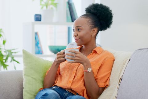 BRIGITTE Diät 2024: Frau trinkt auf dem Sofa Kaffee