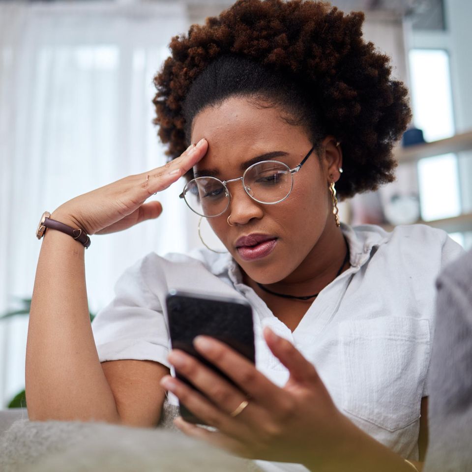 Frustrierte junge Frau blick auf ihr Smartphone