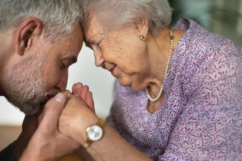 Ein Mann küsst die Hände einer älteren Frau