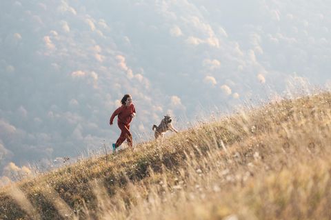 Persönlichkeits-Horoskop 2024: Eine Frau läuft mit ihrem Hund einen Berg hinauf