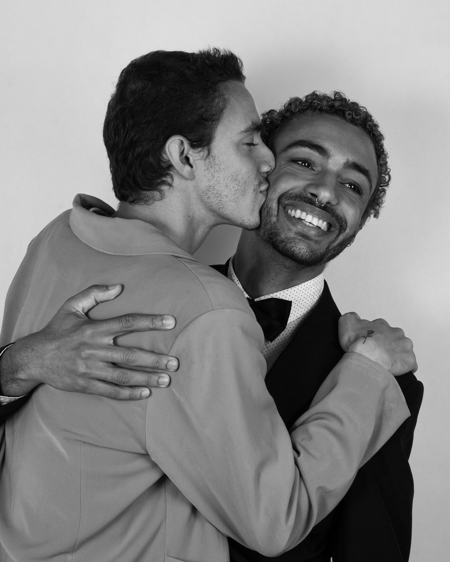 Zwei junge Männer, einer küsst den anderen liebevoll auf die Wange