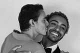 Zwei junge Männer, einer küsst den anderen liebevoll auf die Wange
