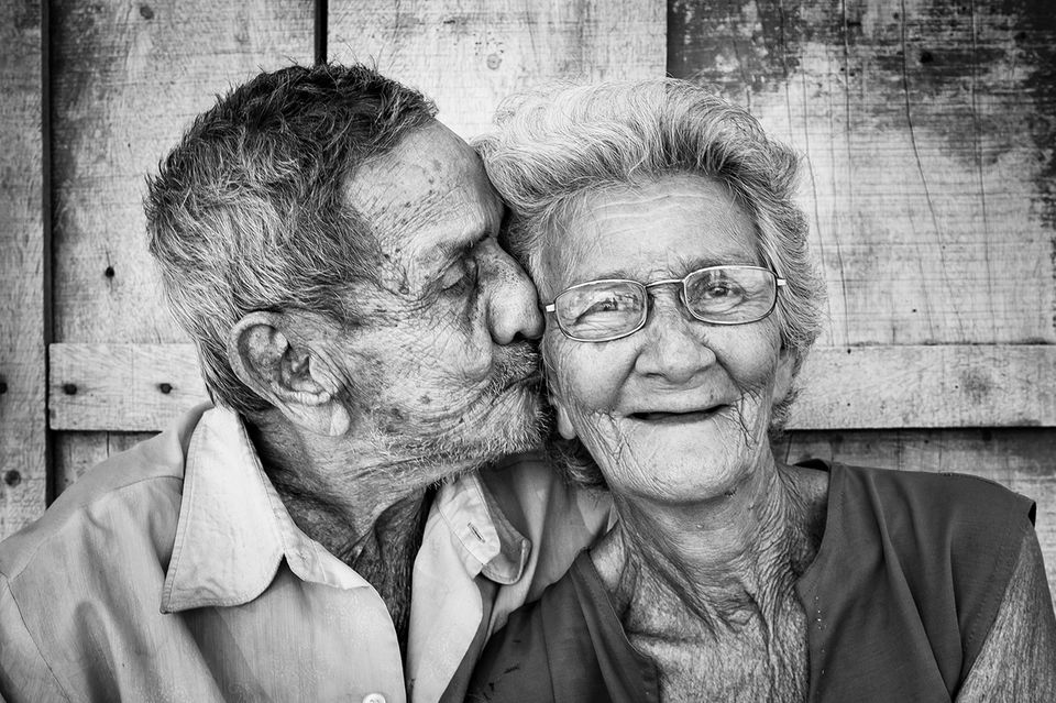 Ein älterer Mann küsst eine Frau auf die Wange