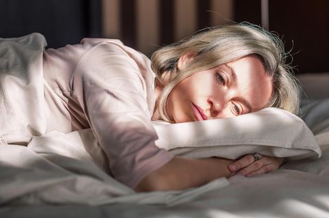 Eine Frau liegt müde in ihrem Bett