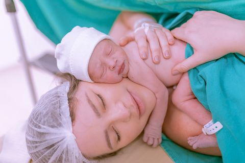 Eine Mutter hält ihr Neugeborenes