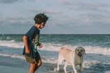 Ein Junge spielt am Strand mit einem Hund
